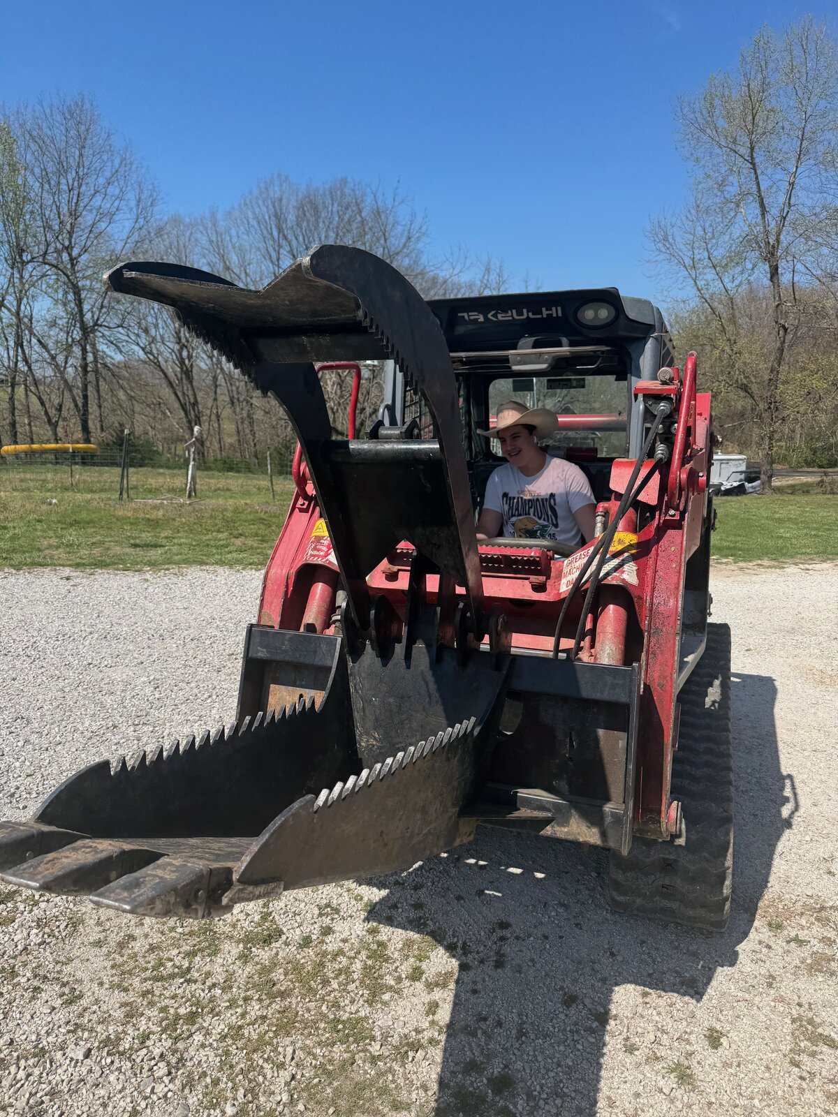 GHR skid steer with grapple attachment on a gravel driveway