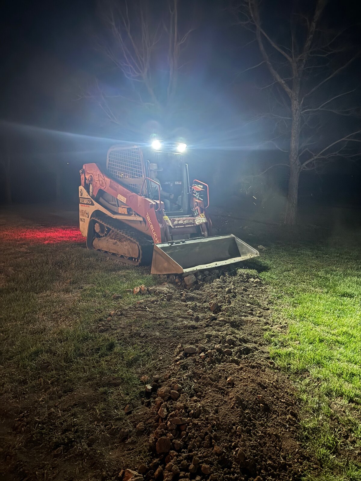 GHR skid steer working an evening job with headlights on